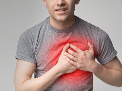 Young man having heart ache, holding hand on chest. Heart attack or stroke