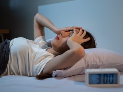 Asian women opened eyes lying on the bed have an insomnia problems.