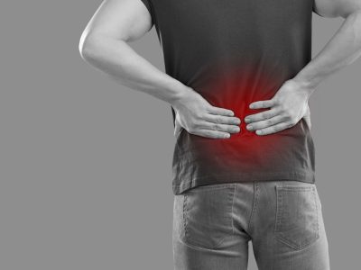 Black and white picture of unhealthy man on studio background struggle with backache. Pain in lower back or kidneys. Unwell guy have low spine ache, suffer from painful feeling spasm or strain.